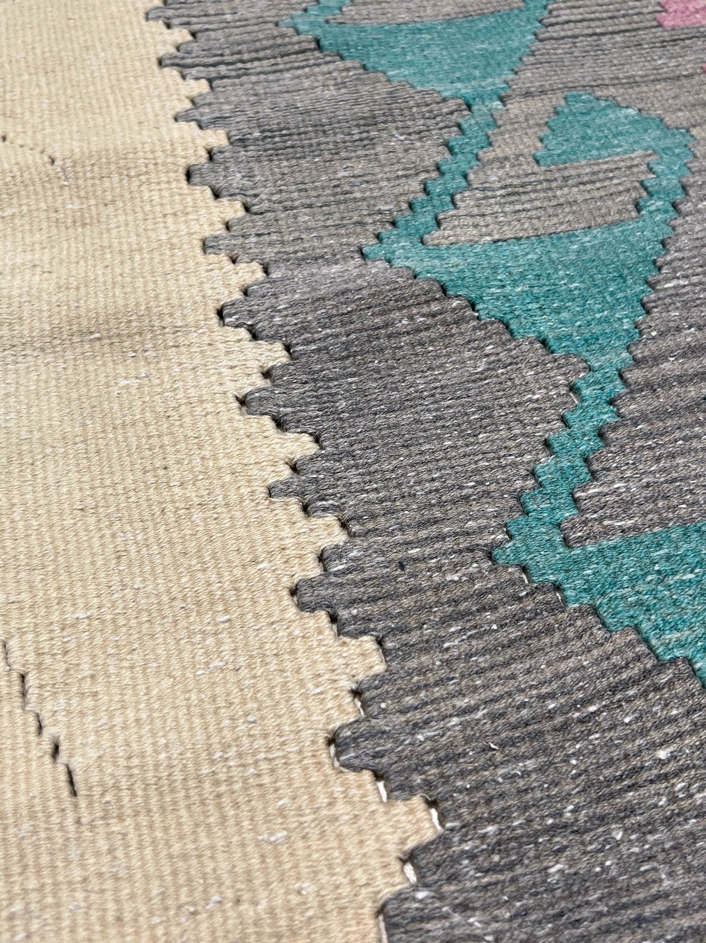 Decorative rug with geometric pattern featuring diamonds and cross symbols on a white background. Vintage Turkish kilim rug, 5x7. 