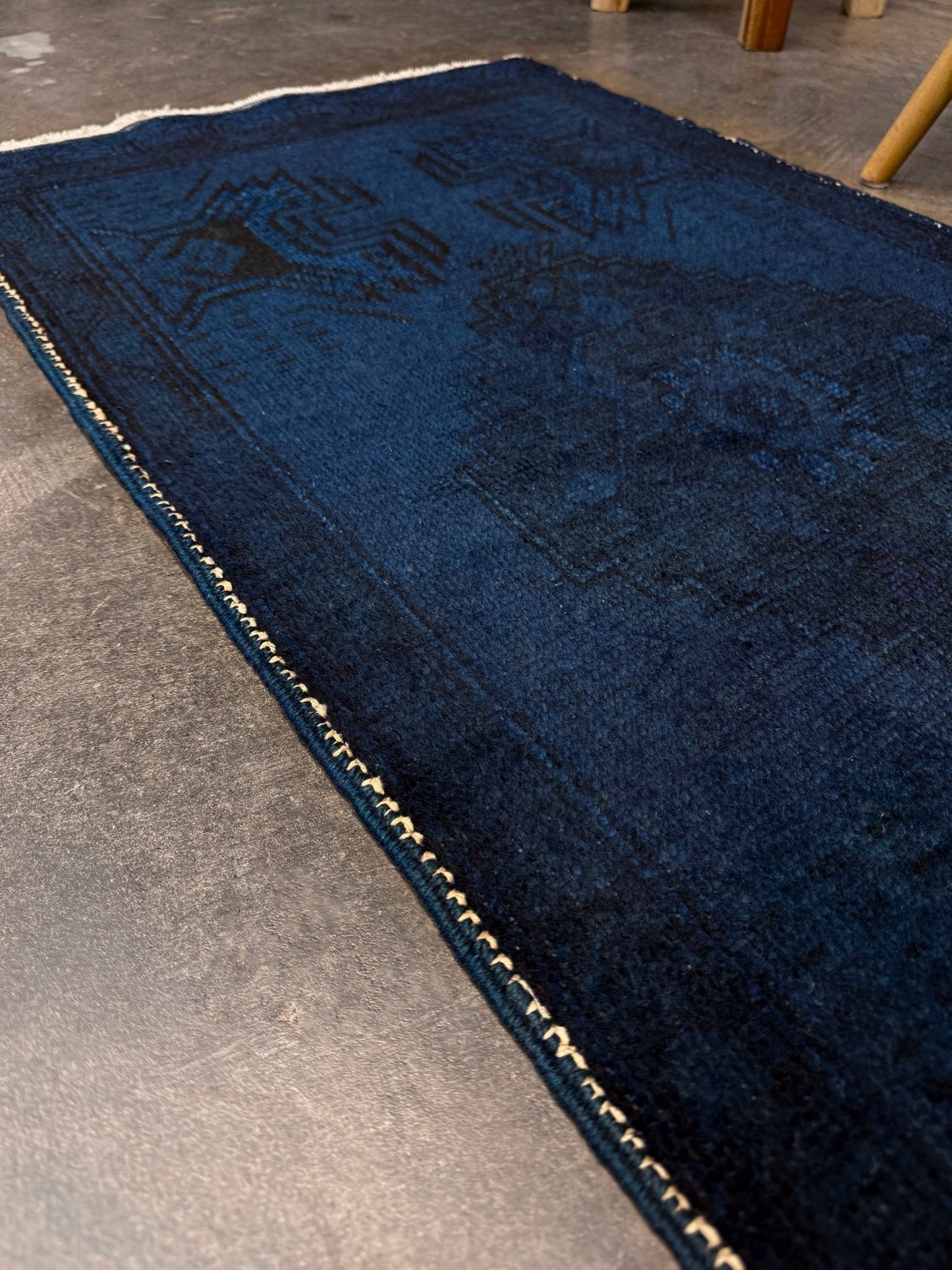 Turkish overdyed Yastik rug in deep indigo and midnight blue, with subtle tribal motifs visible beneath the saturated overdye. Hand-knotted wool, 20x40 inches. One-of-a-kind piece from Indigo Rugs, the best rug shop in the San Francisco Bay Area (Burlingame, CA). Free shipping included.