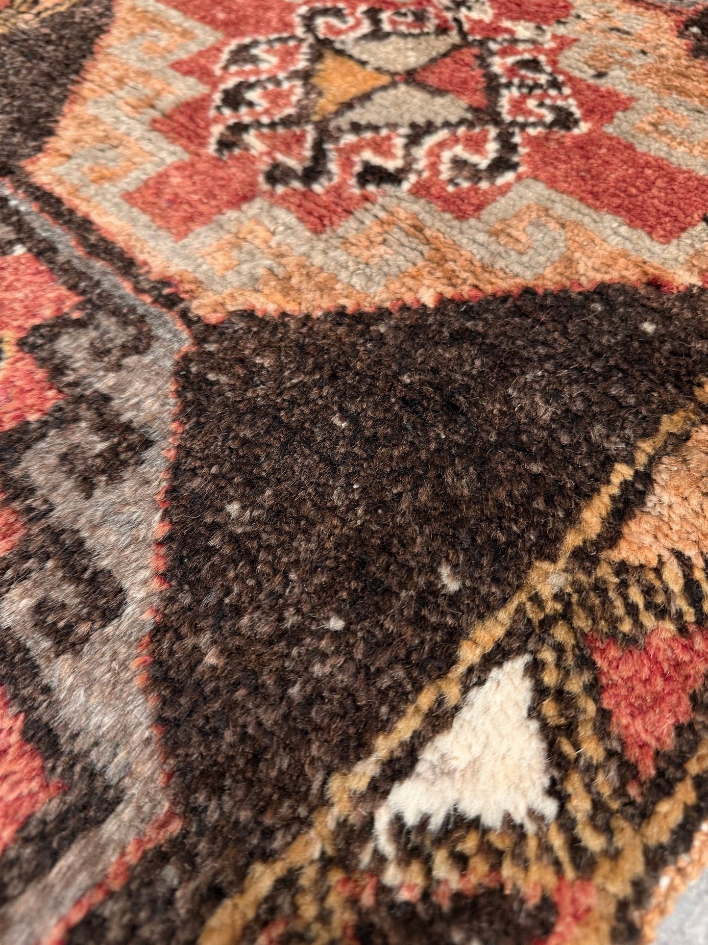Vintage Turkish mini rug 21x39 with terracotta and brown geometric medallion design, handmade wool rug with earthy tones, perfect for entryway or bedside, from Indigo Rugs in the San Francisco Bay Area.