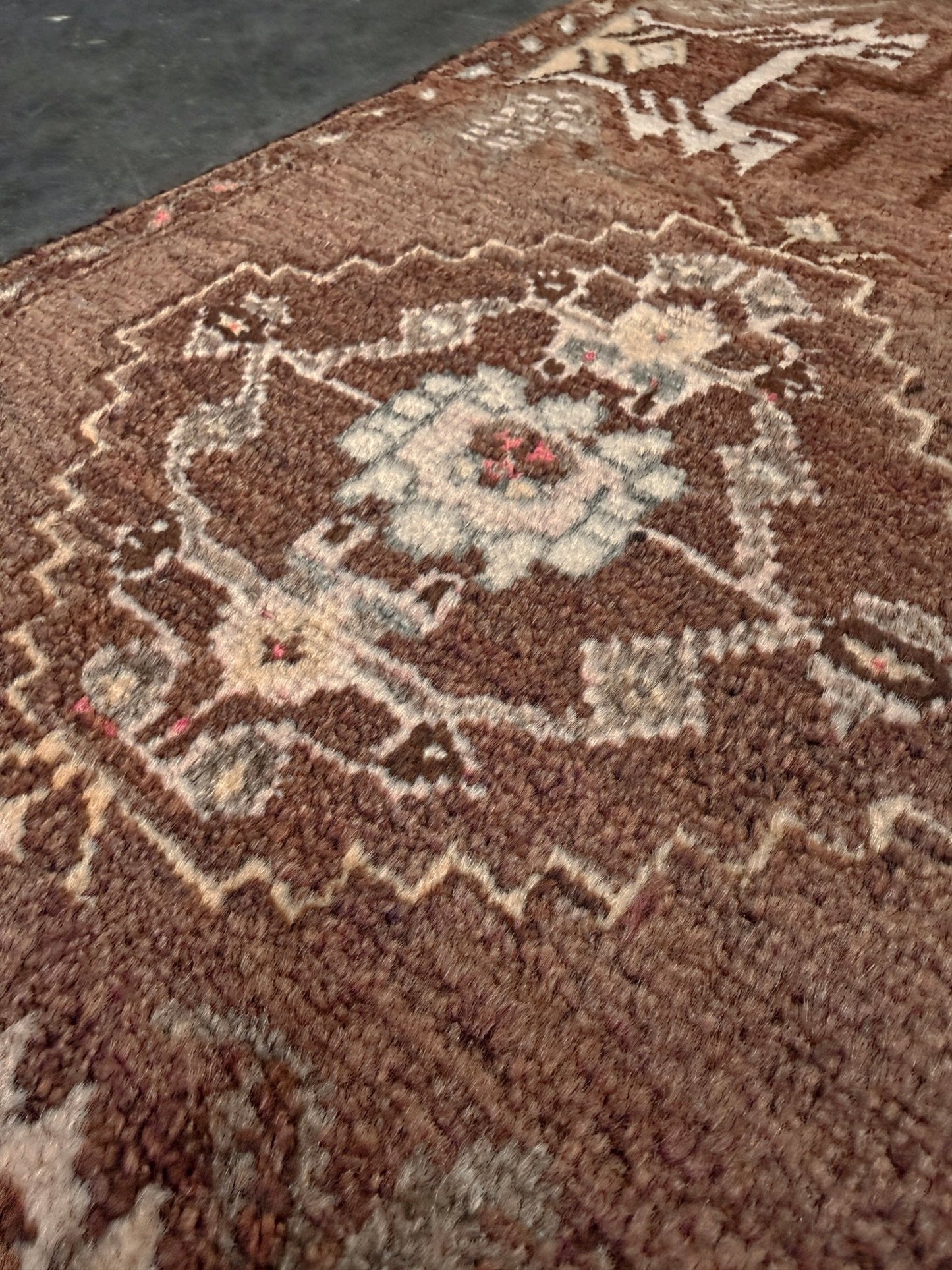 Close-up of a brown patterned Vintage Turkish mini rug with earthy brown field and soft ivory geometric medallion, hand-knotted wool Anatolian village rug, 19x30 small accent rug for bedside, entryway, or wall art. From Indigo Rugs, Burlingame — San Francisco Bay Area.