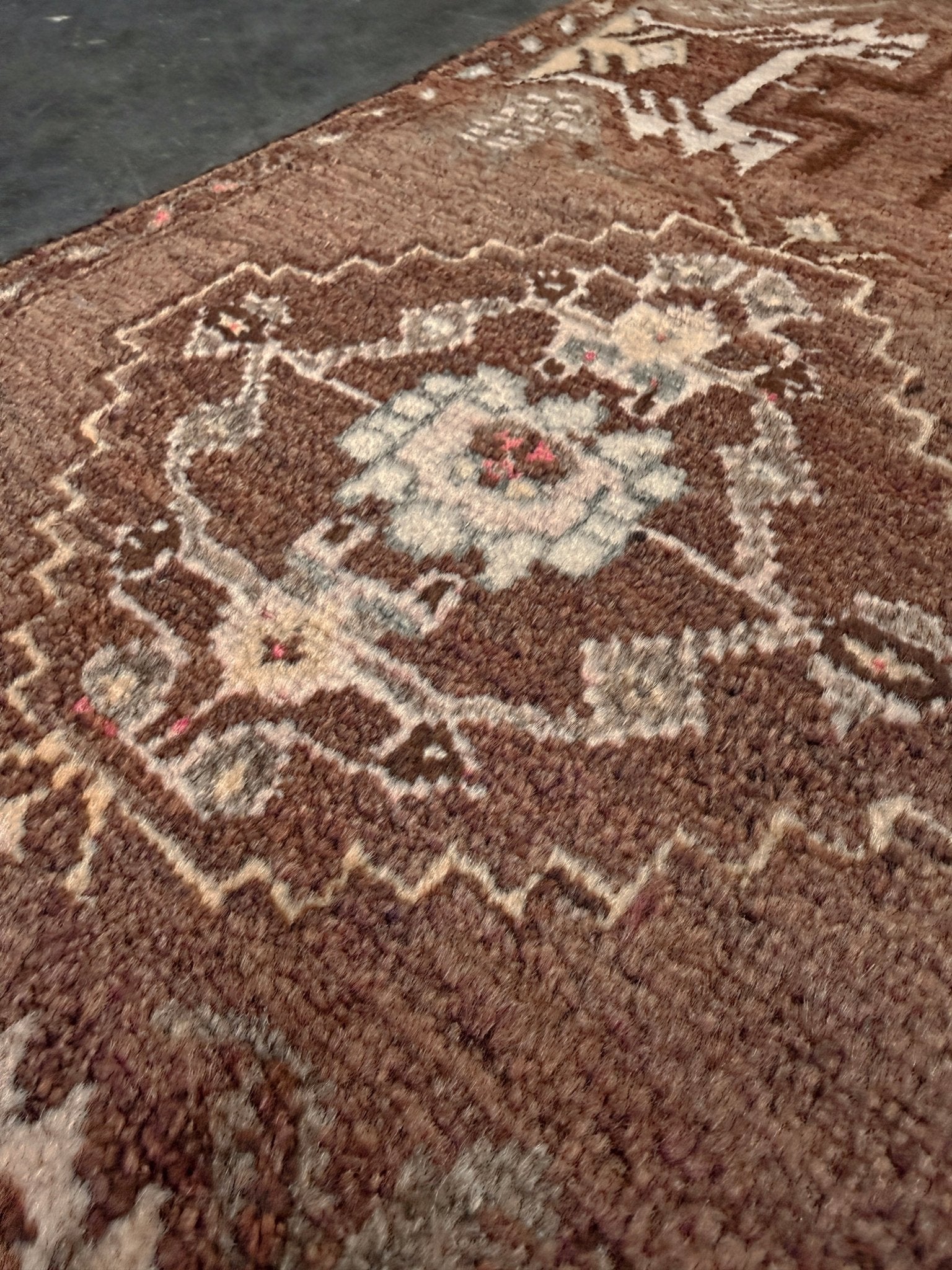 Close-up of a brown patterned Vintage Turkish mini rug with earthy brown field and soft ivory geometric medallion, hand-knotted wool Anatolian village rug, 19x30 small accent rug for bedside, entryway, or wall art. From Indigo Rugs, Burlingame — San Francisco Bay Area.