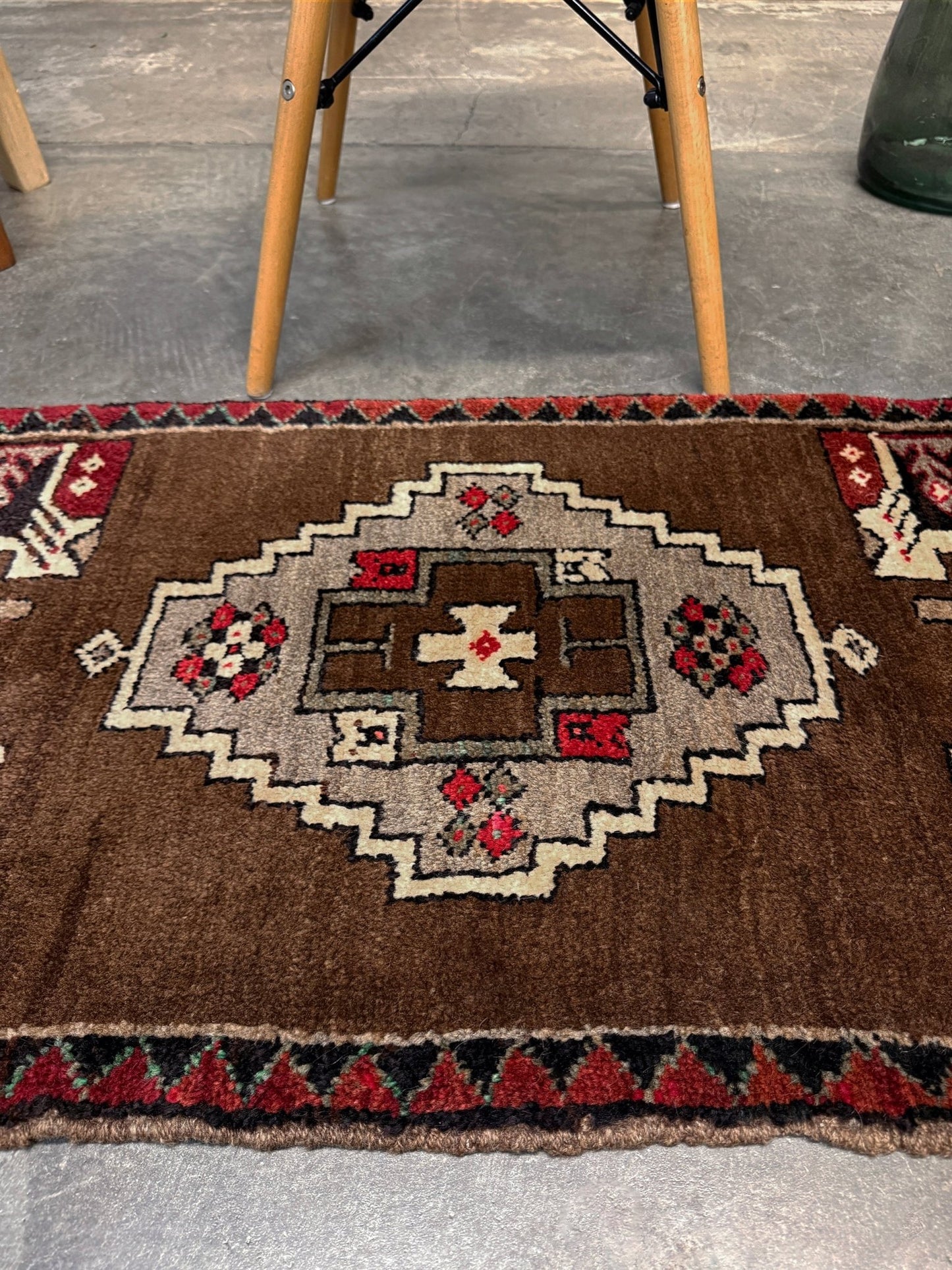 Vintage Turkish Yastik mini rug in walnut brown with taupe and camel medallion, espresso outlines, ivory highlights, and crimson red accents. Hand-knotted wool, 21x37 inches. One-of-a-kind rug from Indigo Rugs, the best rug shop in the San Francisco Bay Area (Burlingame, CA). Free shipping included.