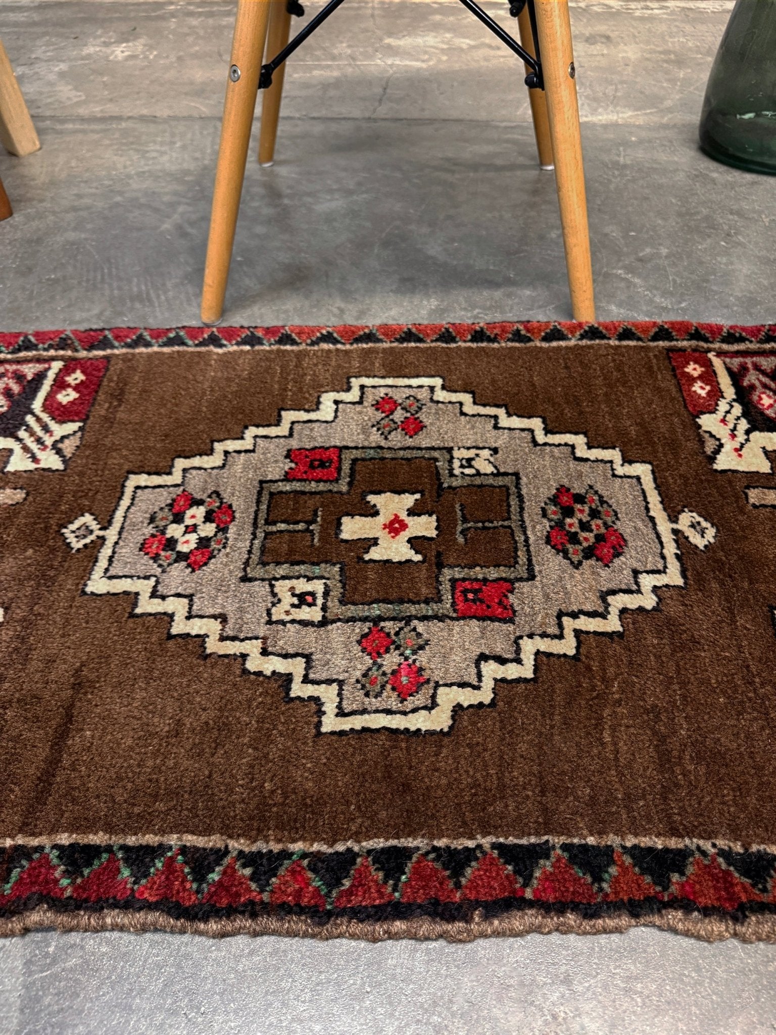 Vintage Turkish Yastik mini rug in walnut brown with taupe and camel medallion, espresso outlines, ivory highlights, and crimson red accents. Hand-knotted wool, 21x37 inches. One-of-a-kind rug from Indigo Rugs, the best rug shop in the San Francisco Bay Area (Burlingame, CA). Free shipping included.