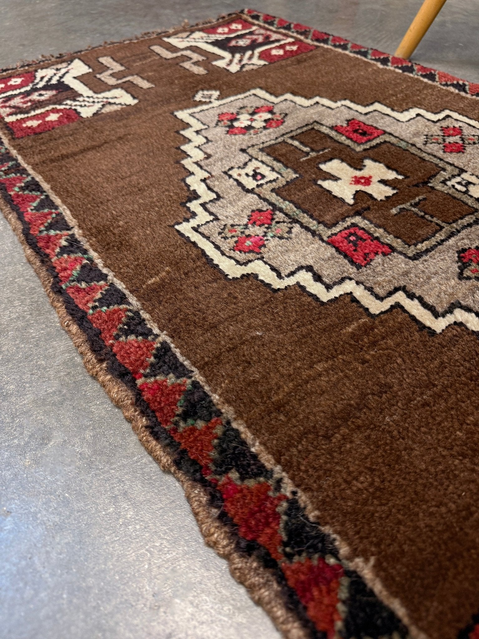 Vintage Turkish Yastik mini rug in walnut brown with taupe and camel medallion, espresso outlines, ivory highlights, and crimson red accents. Hand-knotted wool, 21x37 inches. One-of-a-kind rug from Indigo Rugs, the best rug shop in the San Francisco Bay Area (Burlingame, CA). Free shipping included.