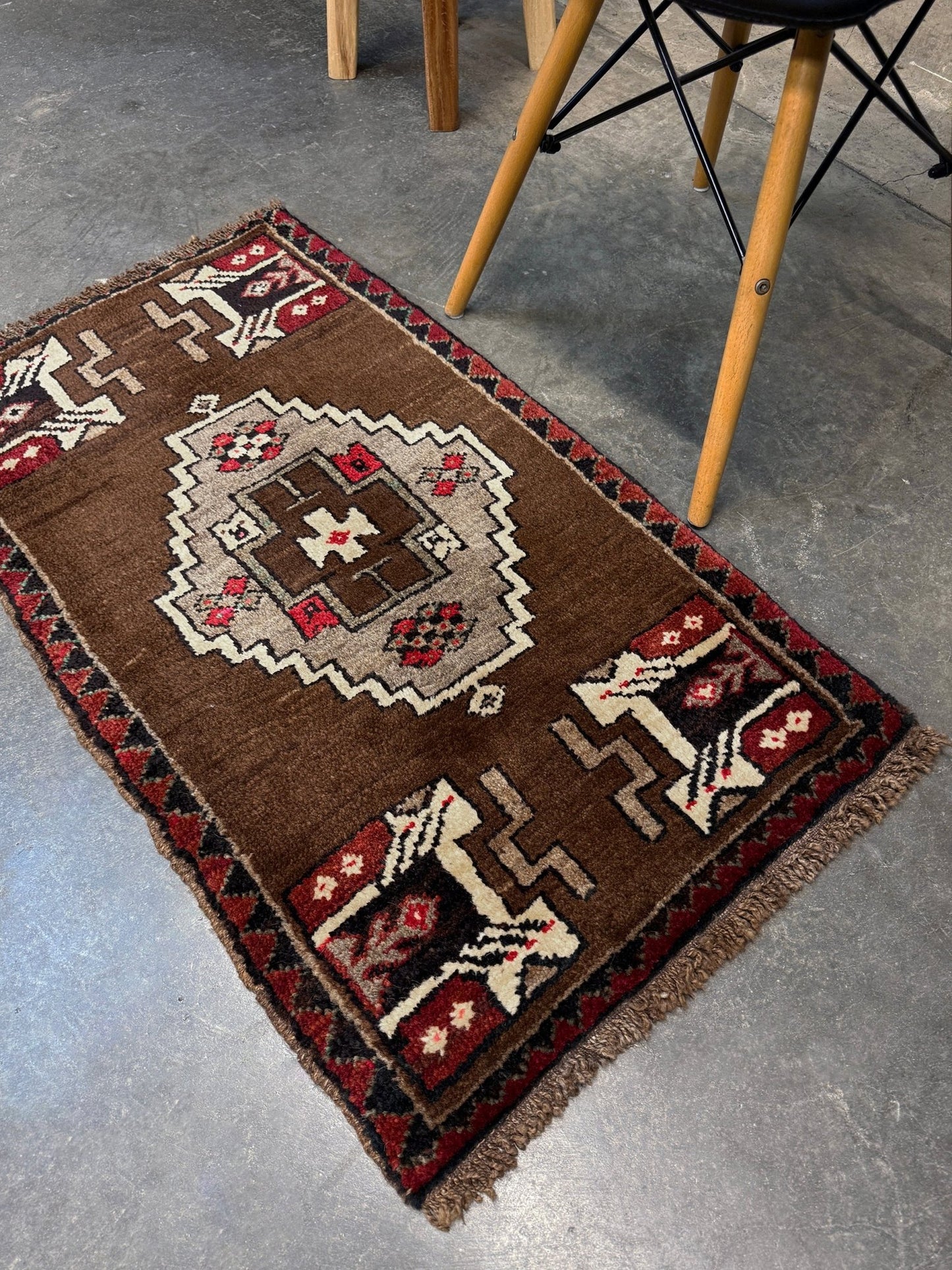 Vintage Turkish Yastik mini rug in walnut brown with taupe and camel medallion, espresso outlines, ivory highlights, and crimson red accents. Hand-knotted wool, 21x37 inches. One-of-a-kind rug from Indigo Rugs, the best rug shop in the San Francisco Bay Area (Burlingame, CA). Free shipping included.